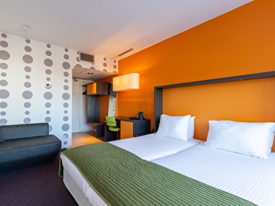 A hotel room with two neatly made beds, nightstands, and lighting, creating a cozy and relaxing atmosphere.